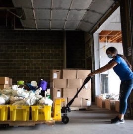 An volunteer at La Colaborativa transporting products in a cart for residents in the City of Chelsea.