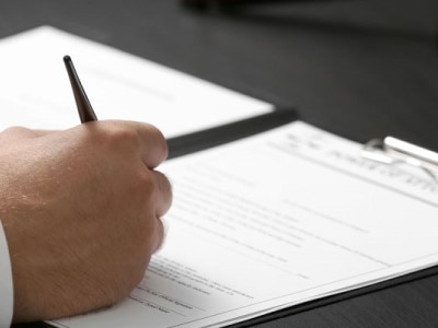 A hand signing a form