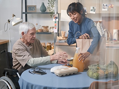 A homemaker delivers groceries to an older adult