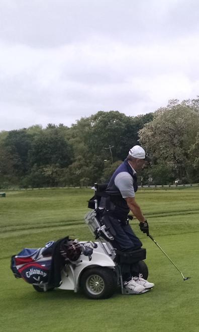 A golfer is using a Paragolfer to raise themselves up to make a putt.
