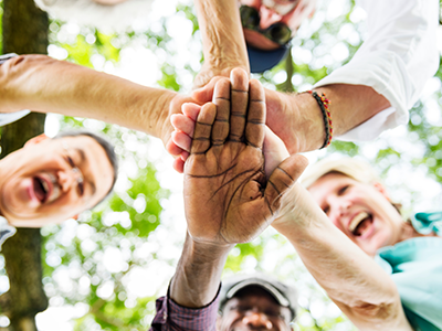 a group of older adults stands in a circle with their hands together
