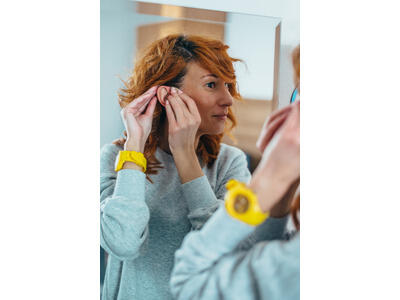 A woman adjusting her cochlear implant