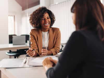 Two people at a table smiling and doing paperwork